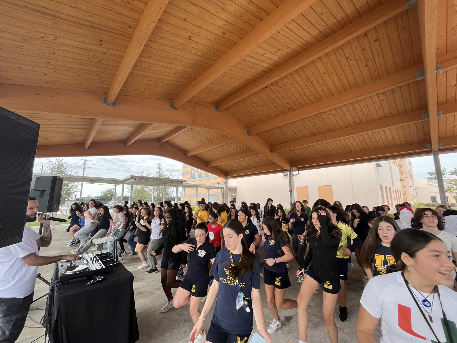DJ Tury performing at an outdoor school pep rally with students dancing