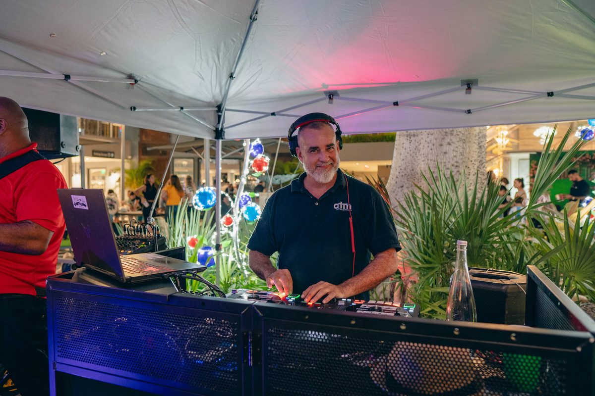 ATM DJ in a branded polo mixing under the canopy at the Coconut Grove Tree Lighting