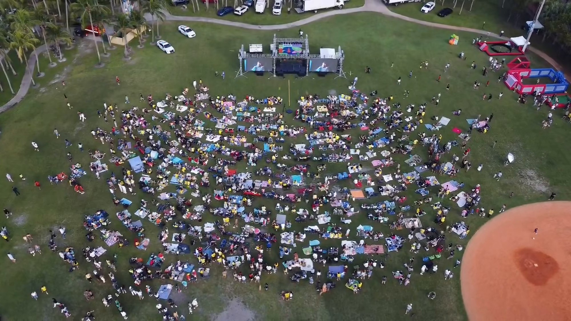 Aerial view of hundreds of people on the field facing ATM's stage and video walls