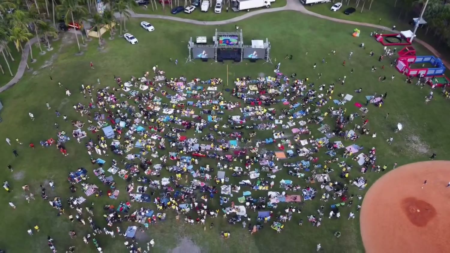 Aerial view of hundreds of people on the field facing ATM's stage and video walls