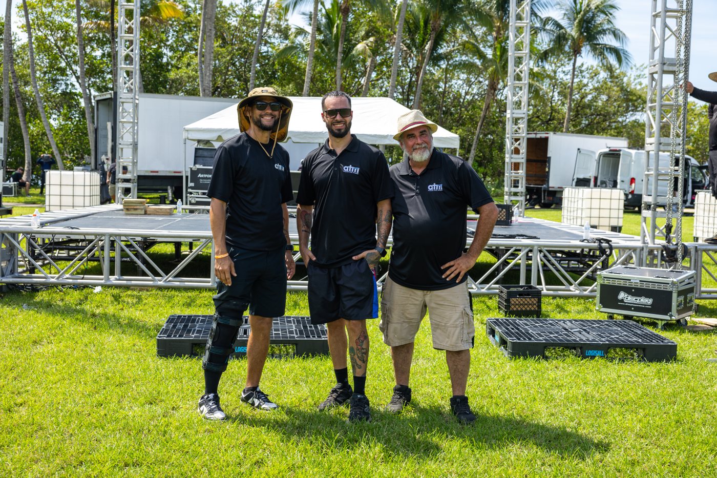 Three members of the ATM Sounds and Events team in branded polos in front of the stage build